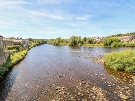 A view of a river with houses and trees at The Railway Apartment in Hexham