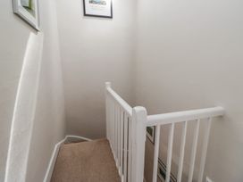 A staircase with a handrail and framed pictures at Cloud Cottage in Ambleside