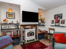 A living room with a television and bookshelf at Moon Cottage White Cross Bay Holiday Park near Troutbeck Bridge