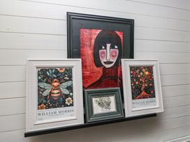 Artworks on a shelf including portraits and nature-themed prints at Moon Cottage White Cross Bay Holiday Park near Troutbeck Bridge