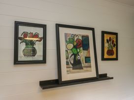 Three framed paintings on a shelf at Moon Cottage in White Cross Bay Holiday Park near Troutbeck Bridge