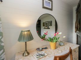 A dressing table with a lamp and flowers at Moon Cottage White Cross Bay Holiday Park near Troutbeck Bridge