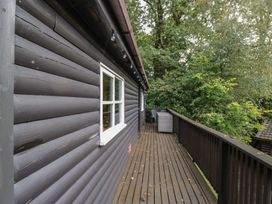 An outdoor area with wooden decking and a view of trees at Moon Cottage near White Cross Bay Holiday Park near Troutbeck Bridge