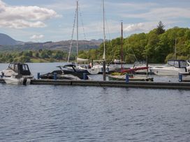 Boats docked at a marina with mountains in the background at Moon Cottage White Cross Bay Holiday Park near Troutbeck Bridge