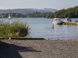 A waterfront scene with boats and a man on a paddleboard at Moon Cottage near White Cross Bay Holiday Park near Troutbeck Bridge