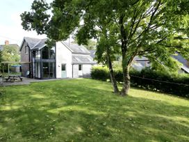A house in a garden with trees and patio furniture at Hen Stablau in Corwen