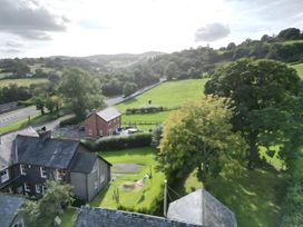 A view of trees and a field with a house at Hen Stablau in Corwen