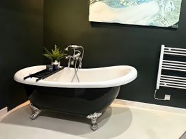 A bathtub with a plant and tray in a bathroom at Hen Stablau Dinmael near Cerrigydrudion