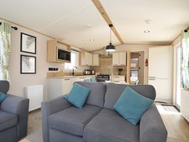 A living room with a sofa and kitchen area at Eden Way 47
