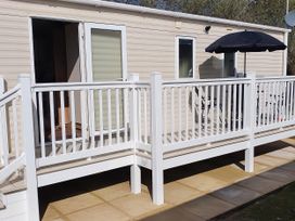 An outdoor deck with railing and an umbrella at Par Sands Holiday Park - 6388, Par