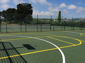 A basketball court with a hoop and adjacent tennis courts at Par Sands Holiday Park - Par