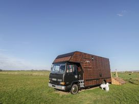 A horsebox parked on grass with a dog nearby at GiGi's Horsebox in Evesham