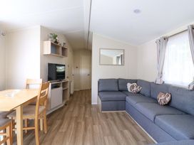 A living room with a sofa and dining area at Singh and Leite Family Caravan St. Osyth