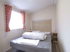 A bedroom with a bed and bedside table at Singh and Leite Family Caravan St. Osyth