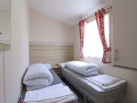 A bedroom with two beds and a window at Singh and Leite Family Caravan St. Osyth