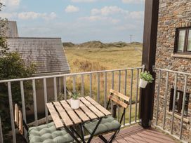 A balcony with a table and chairs overlooking a grassy area at Awel y Môr in Burry Port
