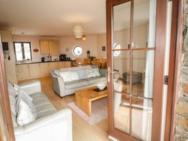 A living room with a sofa and kitchen area at Awel y Môr in Burry Port