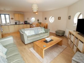 A living room with a sofa, coffee table and kitchen area at Awel y Môr Burry Port
