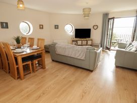 A living room with a dining table and chairs, sofa, and television at Awel y Môr, Burry Port