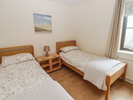 A bedroom with two single beds and a nightstand at Awel y Môr in Burry Port
