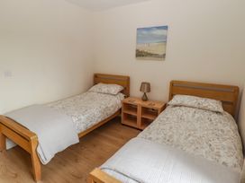 A bedroom with two single beds and a bedside table at Awel y Môr in Burry Port