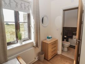 A bedroom with a bathroom and furniture at Awel y Môr, Burry Port
