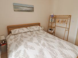 A bedroom featuring a bed, bedside lamp and clothes rack at Awel y Môr in Burry Port