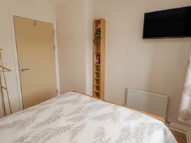 A bedroom with a bed and a television at Awel y Môr in Burry Port
