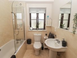 A bathroom with shower, bathtub, toilet, and sink at Awel y Môr Burry Port