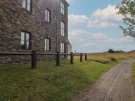 An outdoor view of a stone building and a pathway at Awel y Môr in Burry Port