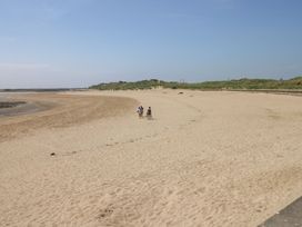 A beach with people walking on sand at Awel y Môr in Burry Port