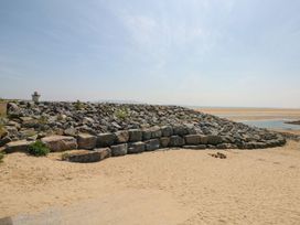A view of rocks and sand near a lighthouse at Awel y Môr in Burry Port