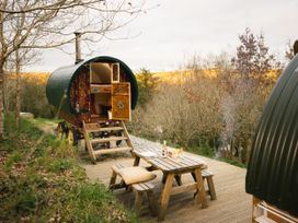 A caravan with a wooden table and chairs outside at Goldfinch in Launceston