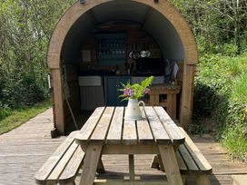 A dining area with a wooden table in an outdoor kitchen at Goldfinch in Panson Mill near Ashwater