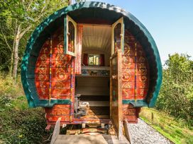 A wooden caravan with open doors and a view of the surrounding landscape at Goldfinch in Panson Mill near Ashwater