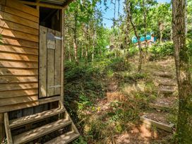 A wooden structure with steps leading to a pathway in a forest at Goldfinch, Panson Mill near Ashwater