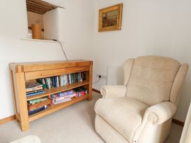 A snug with a bookshelf and a recliner chair at Bubbs Cottage