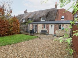 A house with a thatched roof and bench in the outdoor area at Bubbs Cottage