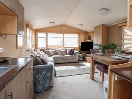 A living room with a sofa and dining area at Caravan 596 in Prestatyn
