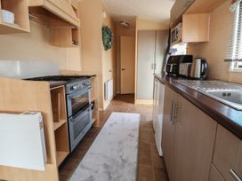 A kitchen with stove, refrigerator, sink and cabinets at Caravan 596 in Prestatyn