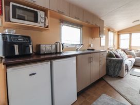 A kitchen area with appliances and a sofa at Caravan 596 Prestatyn