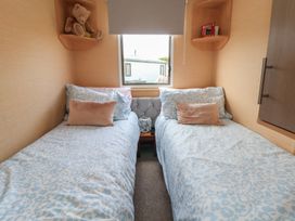 A bedroom with two beds and a teddy bear at Caravan 596 in Prestatyn