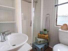 A bathroom featuring a sink, shower, toilet, and storage boxes at Caravan 596 Prestatyn