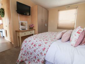 A bedroom with a bed, dresser, and television at Caravan 596 in Prestatyn