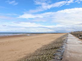 A beach with sand and a walkway near the ocean at Caravan 596 Prestatyn