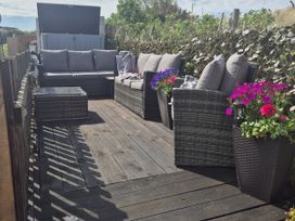 A patio with seating and flower pots at Caravan 596, Prestatyn
