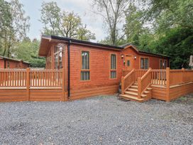 A wooden cabin with a deck and steps at Laughing Duck in Troutbeck Bridge