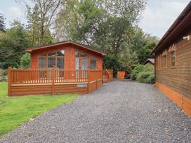 A wooden cabin with decking and gravel driveway at Laughing Duck in Troutbeck Bridge
