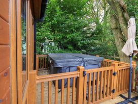 A hot tub on a decking area surrounded by trees at Laughing Duck in Troutbeck Bridge