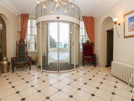 A lobby with a revolving door and two ornate chairs at Costal Lodge at Seaham Hall Seaham
